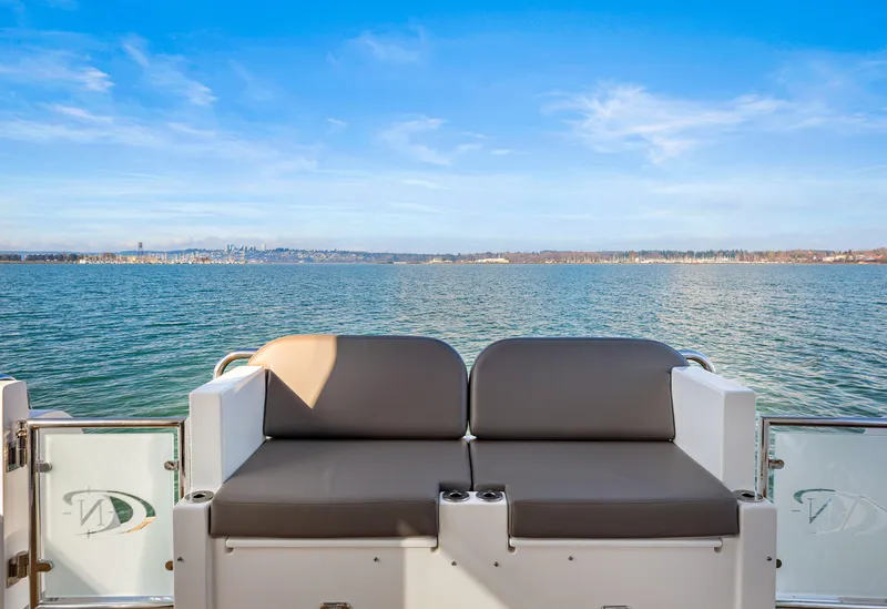 Slide: The Image of North Pacific 450 Pilothouse 2025, rear seating view, overlooking serene blue waters and clear sky. - 32