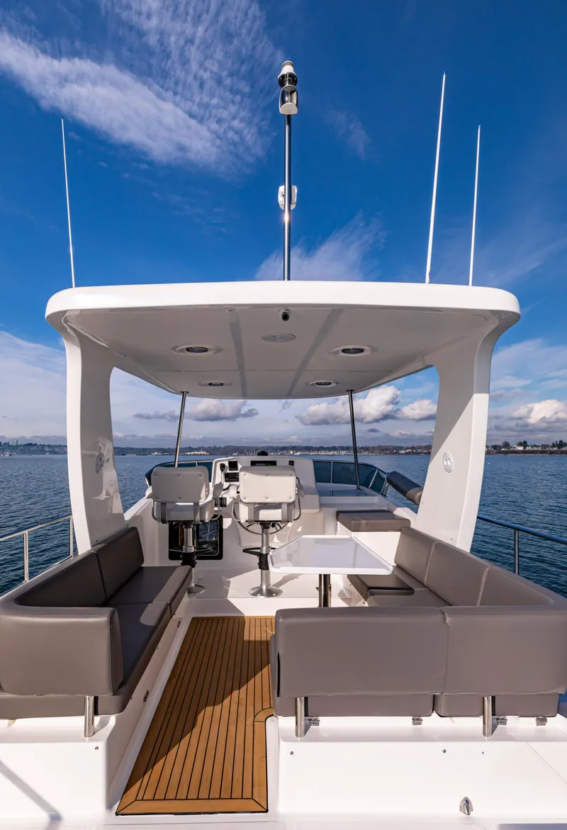 Slide: The Image of 2025 North Pacific 450 Pilothouse yacht with spacious deck and seating, under clear blue sky. - 37