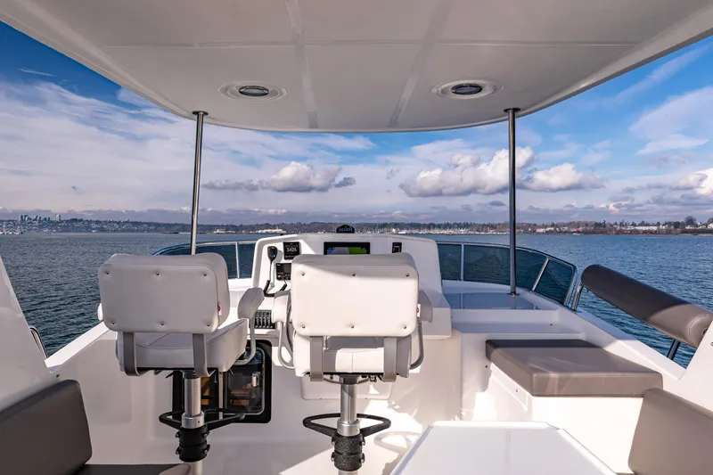 Slide: The Image of 2025 North Pacific 450 Pilothouse boat interior with dual seats and ocean view. - 39