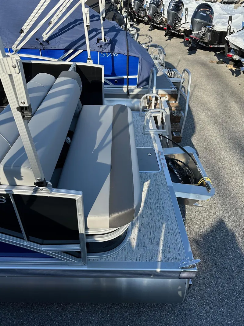 Slide: The Image of 2026 Bennington 188 SLJ pontoon boat with gray seating and blue cover, docked outdoors. - 7