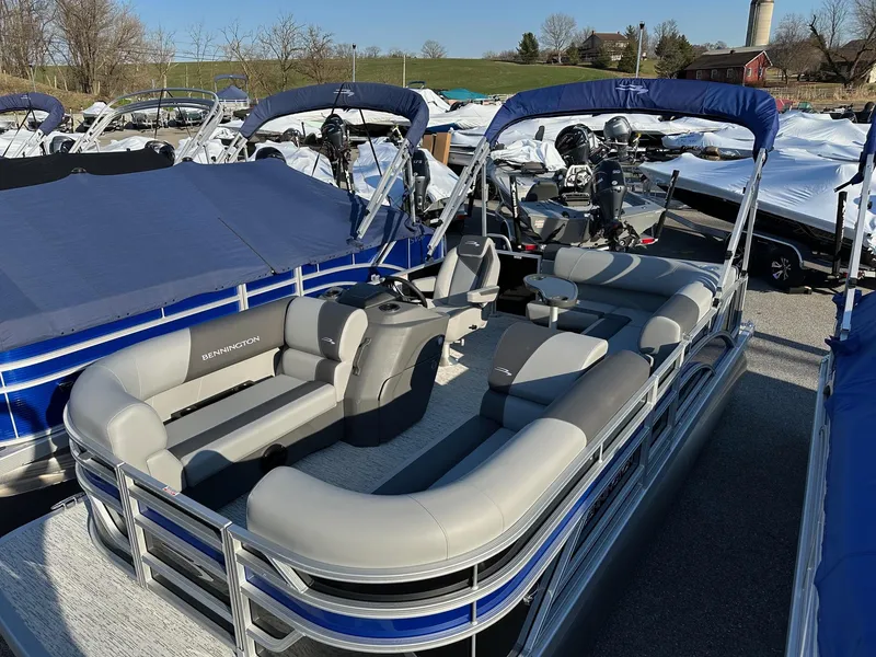 Slide: The Image of 2026 Bennington 188 SLJ pontoon boat with blue canopy and gray seating, docked outdoors. - 18