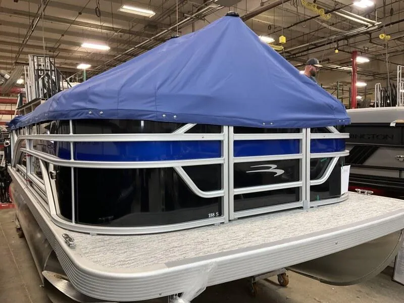 Slide: The Image of 2026 Bennington 188 SLJ pontoon boat with blue cover in a warehouse setting. - 19
