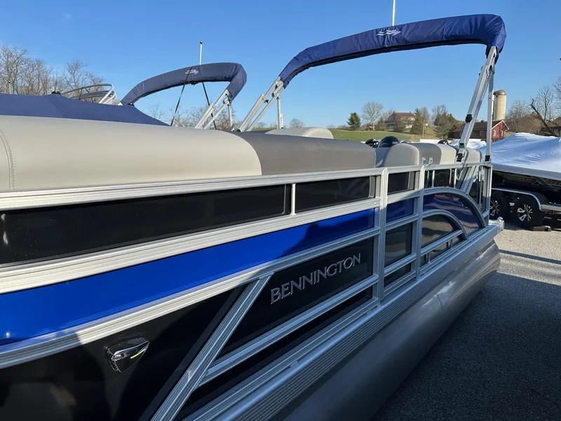 Slide: The Image of 2026 Bennington 188 SLJ pontoon boat with blue accents, docked outdoors. - 5