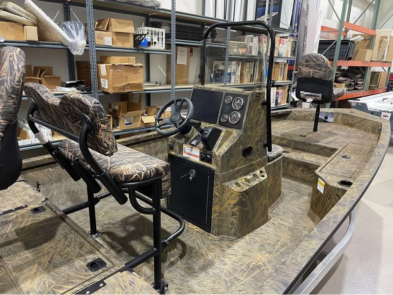 Slide: The Image of 2024 G3 Bay 20 GX boat with camo seats and dashboard in a warehouse. - 24