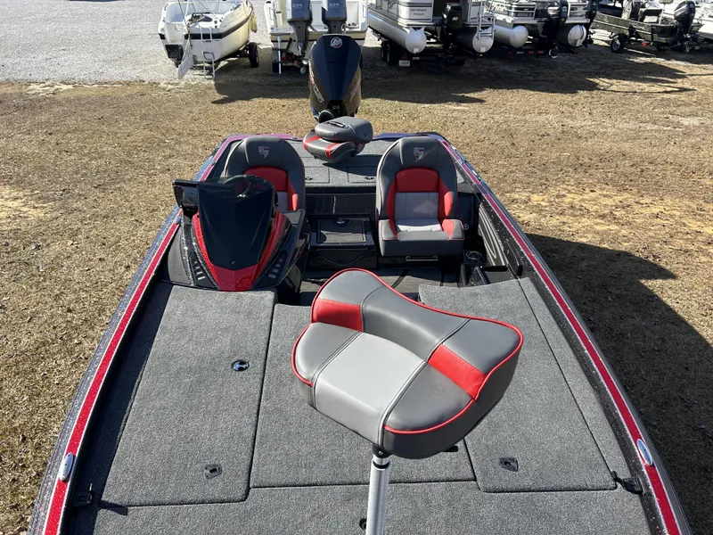 Slide: The Image of 2024 Triton 20XP fishing boat with red and gray seating, parked on grass. - 18