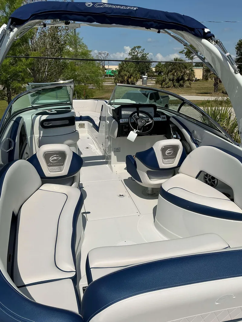 Slide: The Image of 2024 Crownline 270 XSS boat interior with white and blue seating, steering wheel, and open deck. - 6