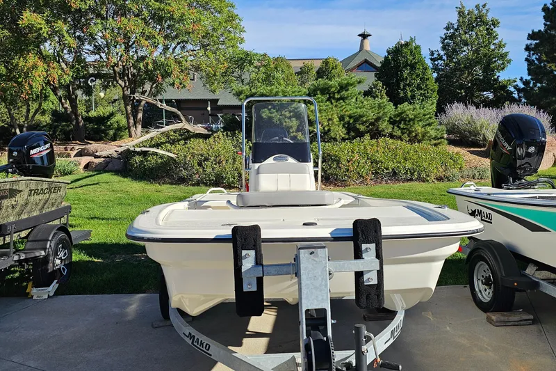 Slide: The Image of 2024 Mako Pro Skiff 13 CC boat on trailer, parked outdoors with lush greenery. - 7