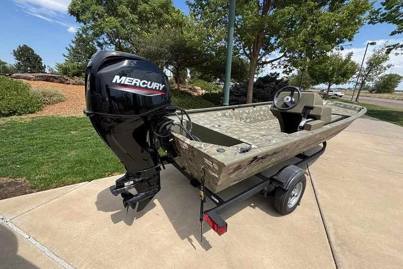 Slide: The Image of 2024 Tracker Grizzly 1648 SC boat with Mercury engine on trailer, parked outdoors. - 6