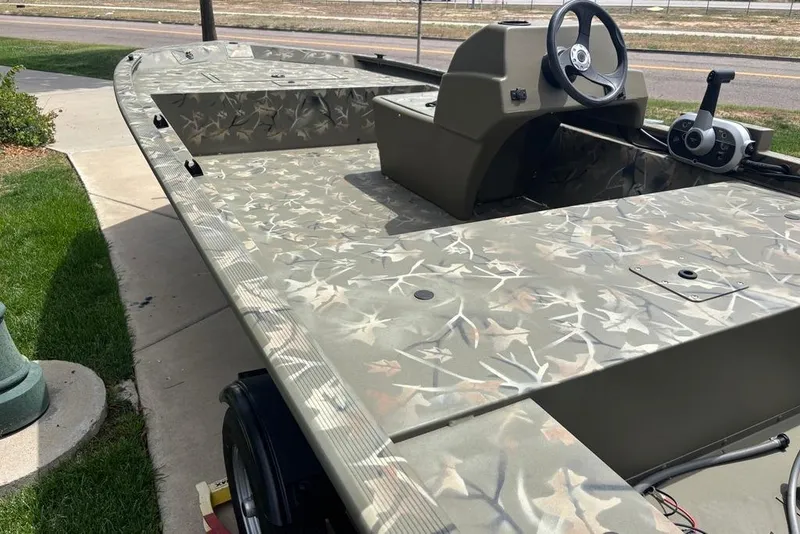 Slide: The Image of 2024 Tracker Grizzly 1648 SC boat with camouflage pattern, parked on a driveway. - 4