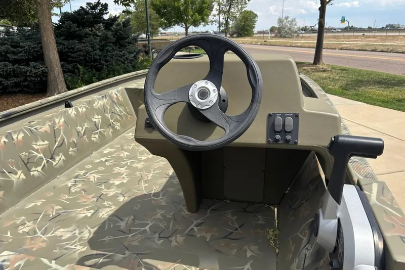 Slide: The Image of 2024 Tracker Grizzly 1648 SC boat interior with camouflage design and steering wheel. - 7