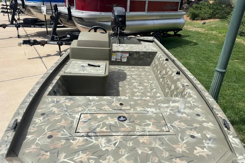 Slide: The Image of 2024 Tracker Grizzly 1648 SC boat with camouflage design, parked outdoors. - 3