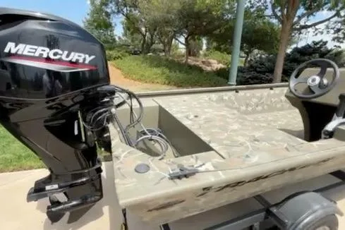 Slide: The Image of 2024 Tracker Grizzly 1648 SC boat with Mercury engine, parked outdoors. - 10