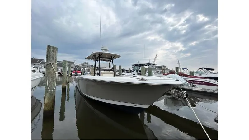 The Image of 2018 NauticStar 2800 XS boat docked at a marina under a cloudy sky. - 0