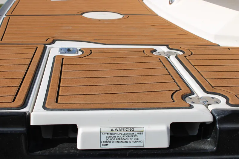 Slide: The Image of 2013 Monterey 234 SS boat deck with teak-style flooring and safety warning label. - 20