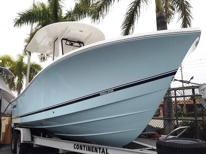 The Image of 2025 Regulator 23 Center Console boat on trailer, surrounded by palm trees. - 0