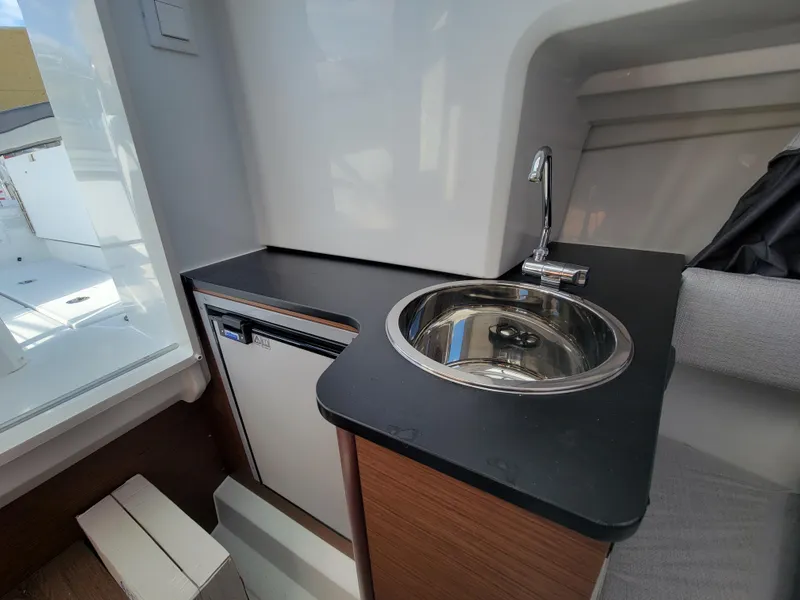 Slide: The Image of Compact kitchenette in the 2024 Jeanneau Leader WA 7.5 boat with sink and mini-fridge. - 13