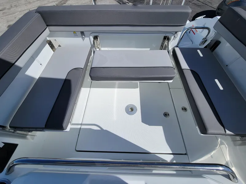 Slide: The Image of 2024 Jeanneau Leader WA 7.5 boat seating area with gray cushions and storage compartments. - 5