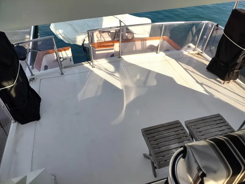 Slide: The Image of 1989 Ocean Alexander 440 CPMY yacht deck with seating and railing, docked on calm water. - 27