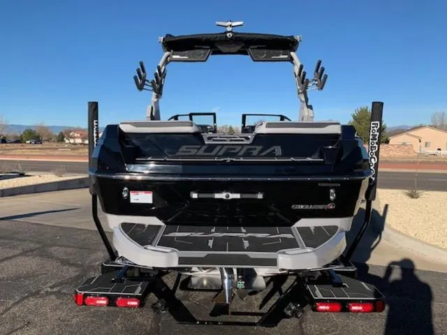Slide: The Image of 2024 Supra SV 550 boat rear view, black and gray, parked outdoors. - 4