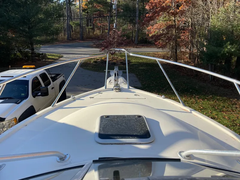 Slide: The Image of 2003 Scout 280 Abaco boat bow view with trees and parked vehicles. - 32