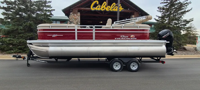 Slide: The Image of 2024 Sun Tracker Party Barge 22 XP3 pontoon boat on trailer outside Cabela's. - 2