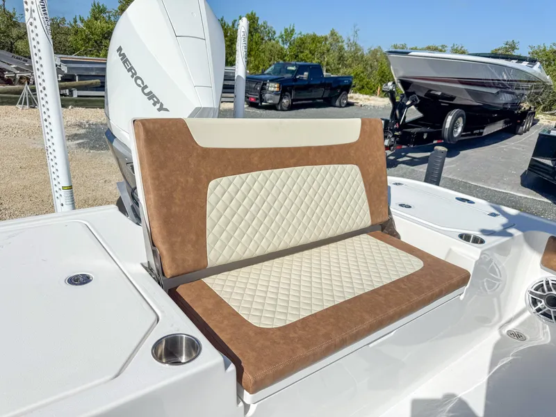 Slide: The Image of 2024 Caymas 26 HB boat with cushioned seating and Mercury engine in a marina setting. - 12