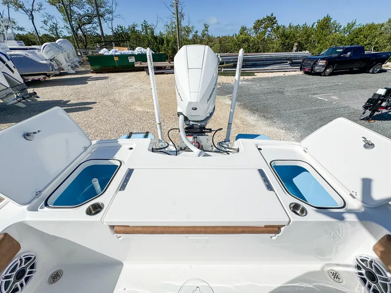 Slide: The Image of 2024 Caymas 26 HB boat with dual livewells and outboard motor in a marina setting. - 13