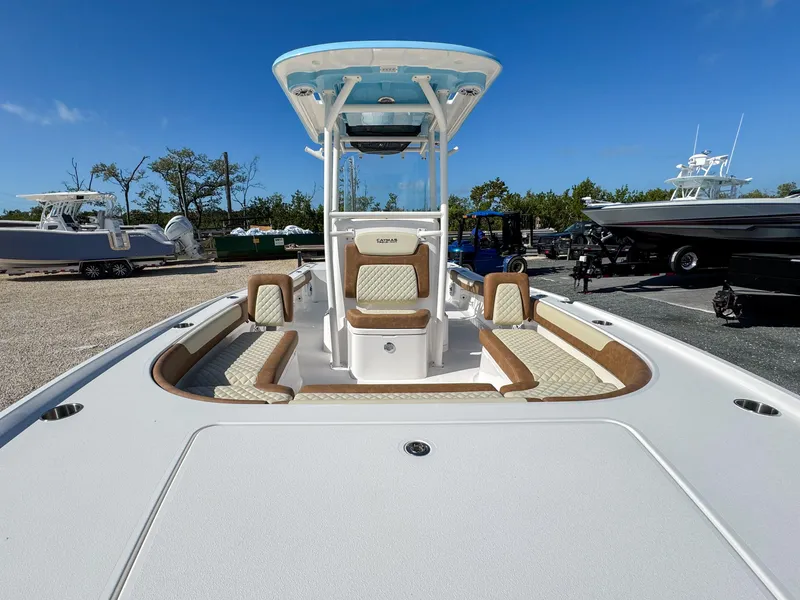 Slide: The Image of 2024 Caymas 26 HB boat with spacious deck and seating, parked outdoors. - 21