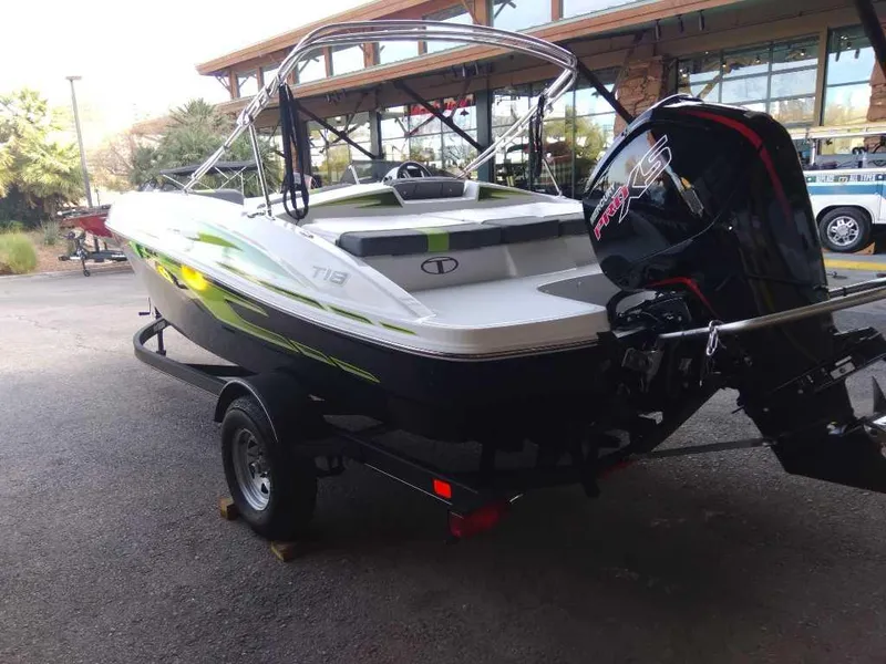 Slide: The Image of 2024 Tahoe T18 boat with outboard motor on trailer, parked outdoors. - 2