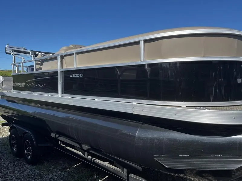 The Image of 2024 Ranger Reata 200C pontoon boat on a trailer under a clear blue sky. - 0