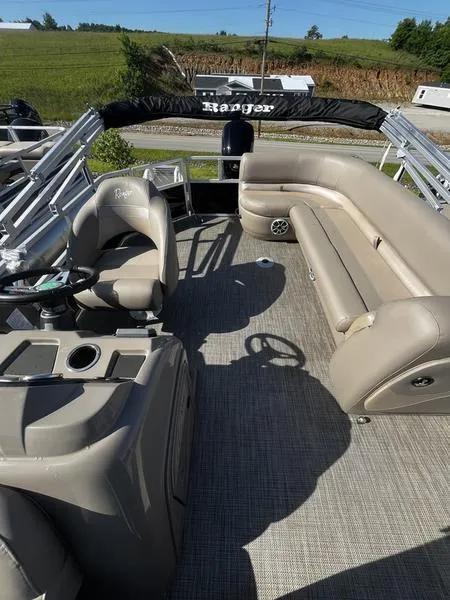 Slide: The Image of 2024 Ranger Reata 200C pontoon boat interior with beige seating and helm. - 6