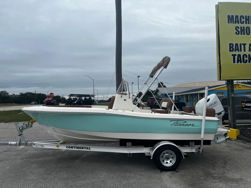 Slide: The Image of 2025 Pioneer 180 Islander boat on trailer, parked near a shop. - 3