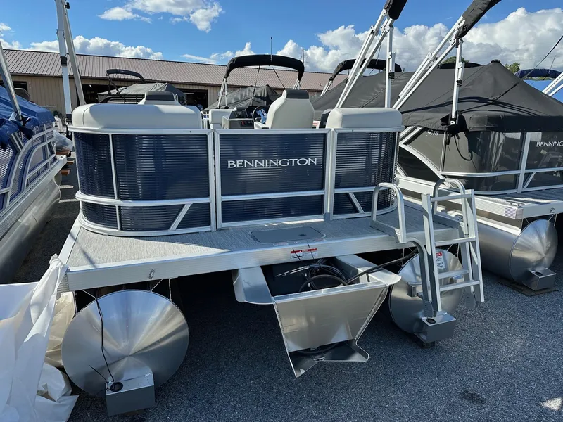 Slide: The Image of 2025 Bennington 20 SSR Quad Bench pontoon boat, silver and blue, docked outdoors. - 17
