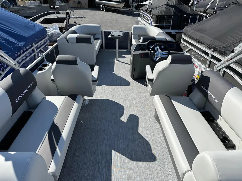 Slide: The Image of 2025 Bennington 20 SSR Quad Bench pontoon boat interior with gray seating and steering console. - 28