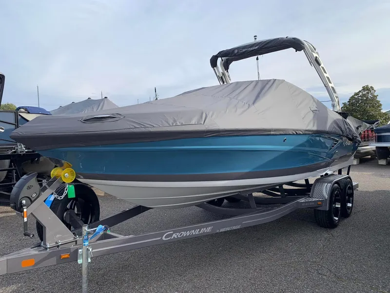 The Image of 2024 Crownline 240 SS boat on trailer in showroom, blue and white exterior. - 0