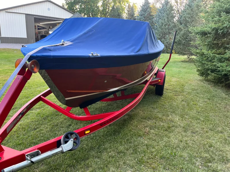 Slide: The Image of 1966 Century Arabian boat on red trailer with blue cover, parked on grass. - 18