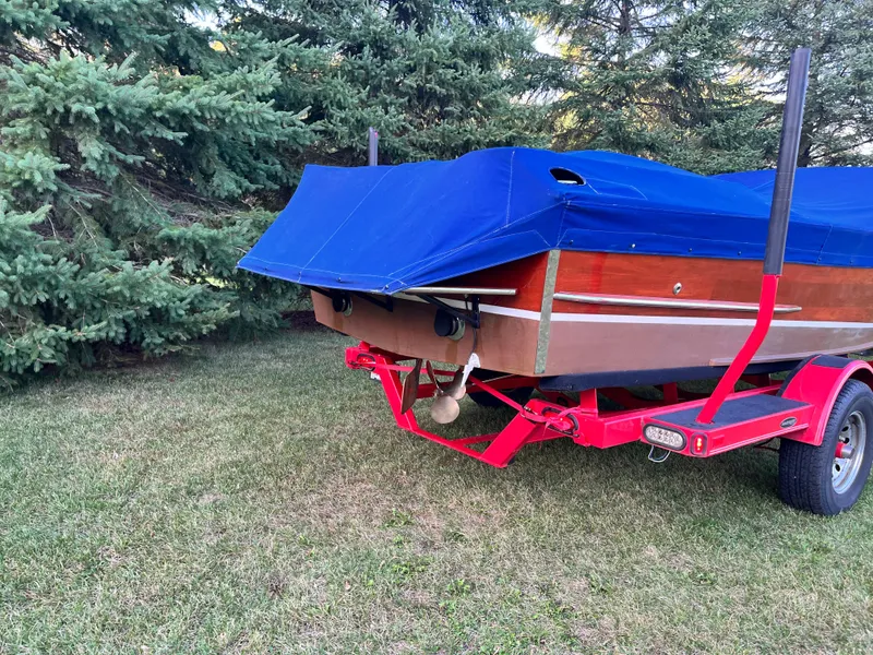 Slide: The Image of 1966 Century Arabian boat on red trailer, covered with blue tarp, parked on grass near trees. - 20