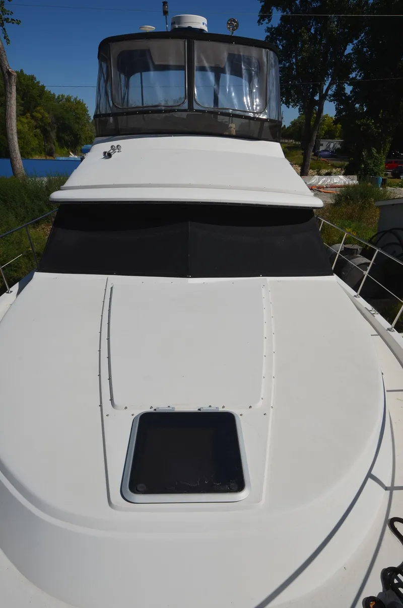 Slide: The Image of 1986 Carver Cockpit 4227 MY yacht, white exterior, docked near trees and water. - 3