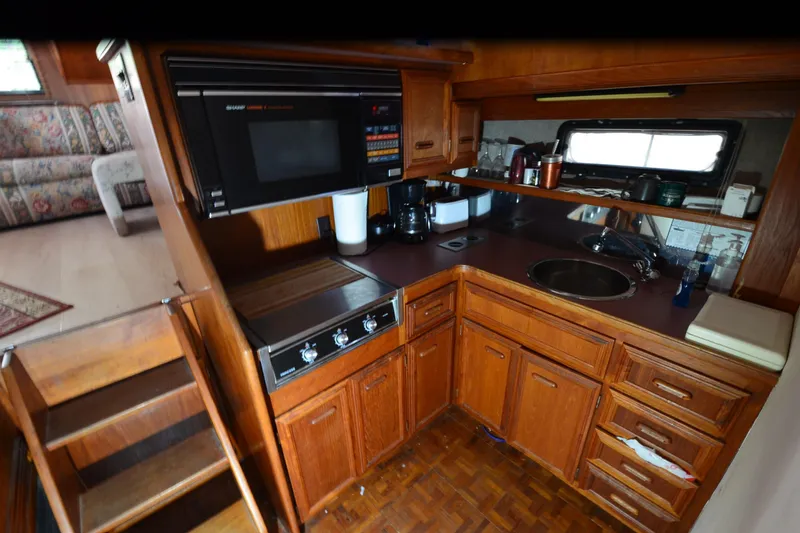 Slide: The Image of 1986 Carver Cockpit 4227 MY kitchen with wooden cabinets, microwave, and sink. - 34