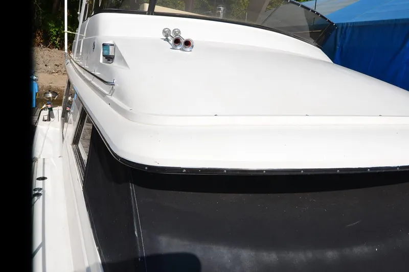 Slide: The Image of 1986 Carver Cockpit 4227 MY boat, white exterior, docked near a blue tarp. - 61