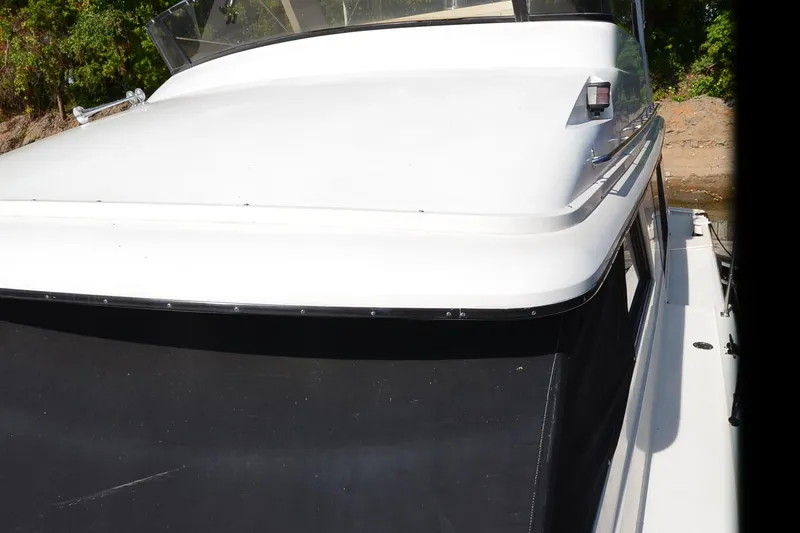 Slide: The Image of 1986 Carver Cockpit 4227 MY boat with white exterior, docked near greenery. - 62