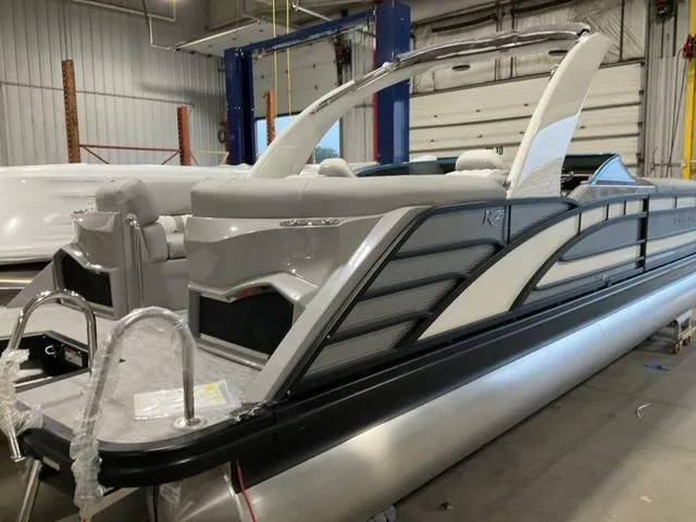 Slide: The Image of 2023 Bennington 25 RFBWA Tritoon boat with quad bench seating in a showroom. - 6