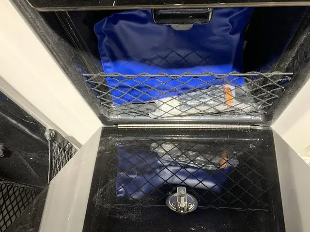 Slide: The Image of Storage compartment of 2023 Yamaha Boats 252XE with netting and blue interior. - 12