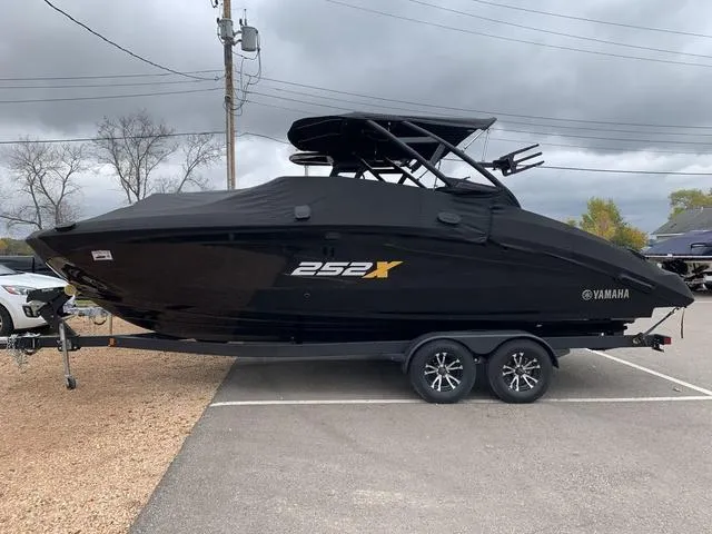 Slide: The Image of 2023 Yamaha Boats 252XE, sleek black design on trailer, parked outdoors. - 26