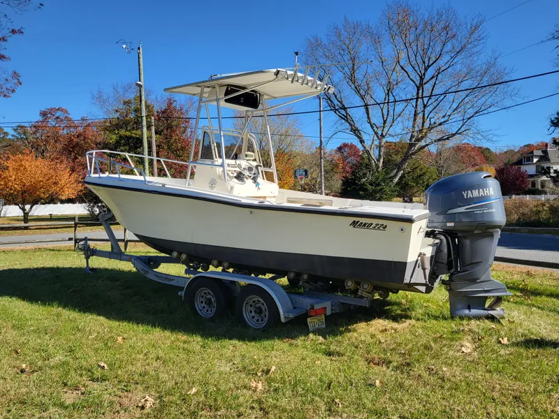 The Image of 1985 Mako 224 CC boat on trailer with Yamaha outboard, parked on grass. - 0