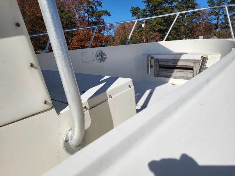 Slide: The Image of 1985 Mako 224 CC boat interior with railing and seating, surrounded by autumn trees. - 4