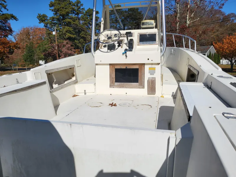 Slide: The Image of 1985 Mako 224 CC boat interior with steering console, white deck, and clear blue sky. - 7