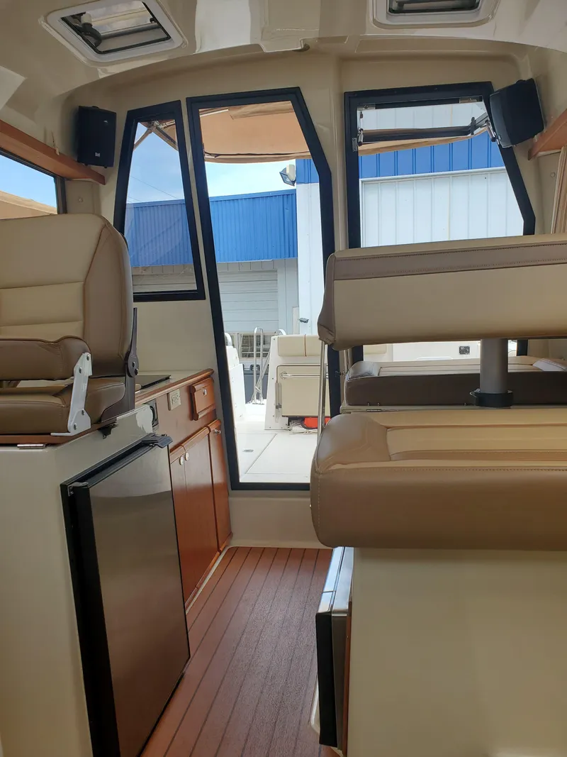 Slide: The Image of 2020 Ranger Tugs 25 interior with beige seating and wood flooring. - 10