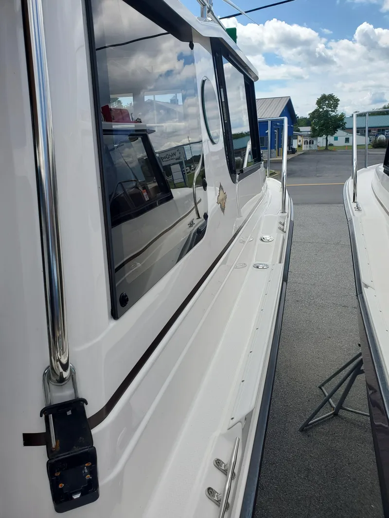 Slide: The Image of 2020 Ranger Tugs 25 boat side view, docked under a partly cloudy sky. - 22