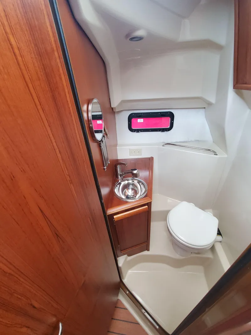 Slide: The Image of 2020 Ranger Tugs 25 boat bathroom with sink, toilet, and wooden cabinetry. - 7
